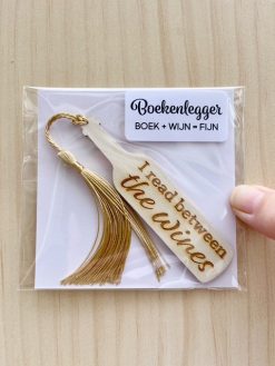 Stop humor tussen je boek Houten boekenlegger in de vorm van een wijnfles met de hilarische quote ‘I read between the wines’. Er hangt een gouden klosje aan zodat het makkelijk zichtbaar is in een boek. Verpakt in een hersluitbaar plastic zakje met kado sticker en kaartje.